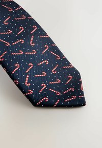 Tengeri kék nyakkendő, piros és fehér cukorpálca mintával, textúrált felülettel és apró fehér kiegészítőkkel az anyagon.