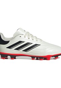 Bota de fútbol blanca con un diseño elegante, rayas negras y una suela vibrante en rojo. Presenta una parte superior texturizada y un sistema de cordones tradicional.
