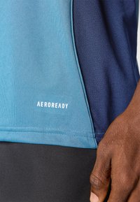 AEROREADY atletska majica s gradijentnim dizajnom u plavim tonovima, glatke teksture, i kontrastnim tamnoplavim bočnim panelom s bijelim logotipom.