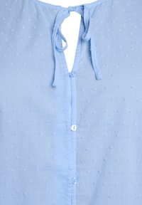 Blusa azzurra chiara con punti testurizzati, patta con bottoni e chiusura con lacci sul retro. Realizzata in un tessuto morbido e leggero.