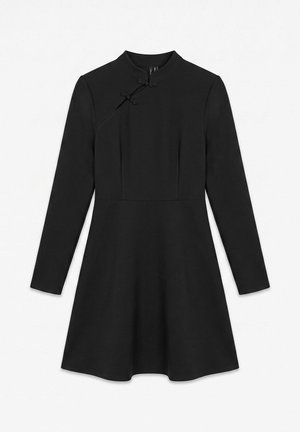 Robe noire à manches longues, à taille ajustée, jupe évasée, col montant et fermetures nouées décoratives à l’épaule.
