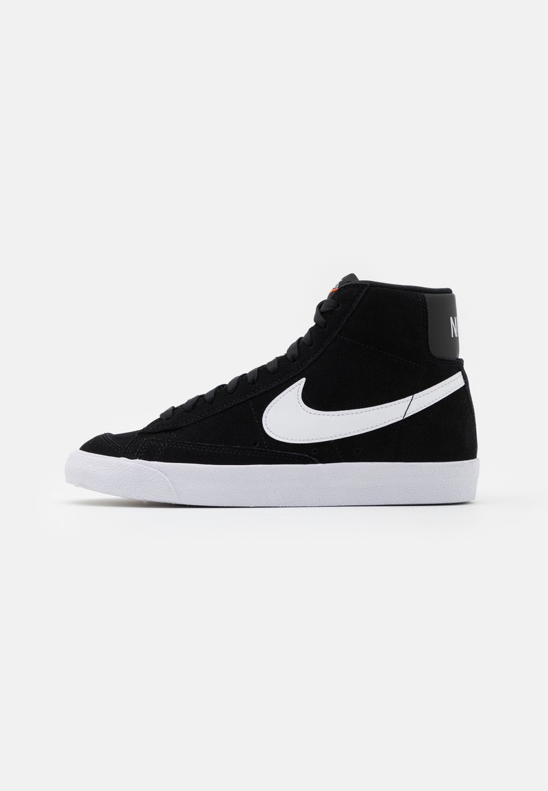 Black high-top sneakers made of suede with a white midsole and swoosh logo. Features flat laces and a padded collar for support.