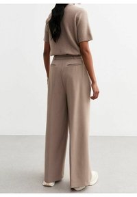 Beige vida byxor med skräddarsydd passform, med en slät textur, två bakfickor och en veck som går ner fram.