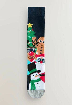 Calcetín negro con diseños festivos, que presenta un árbol de Navidad, un hombre de jengibre, un muñeco de nieve con una bufanda verde y Santa Claus, todo en colores vibrantes.