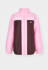 Rosa och brun vindjacka med hög krage, dragkedja, elastiska ärmar och vita randiga detaljer. Har ett strukturerat brunt mönster.