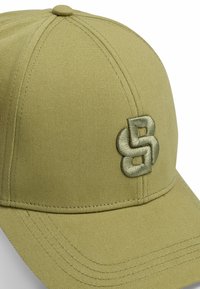 Khaki cap with six-panel design, featuring a raised embroidered logo in matching color, and reinforced stitching on the brim.