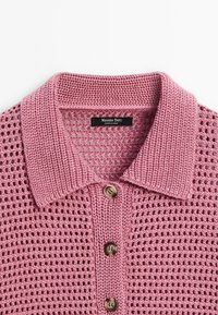 Rosa gestricktes Polohemd mit strukturiertem, offenem Gewebe. Verfügt über einen gerippten Kragen und drei braune Knöpfe an der Vorderseite. Markenlabel sichtbar.