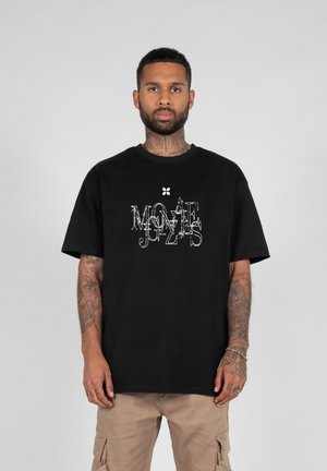 Schwarzes Baumwoll-T-Shirt mit kurzen Ärmeln, das ein abgenutztes weißes Grafiktextdesign zeigt. Rundhalsausschnitt, lockere Passform.