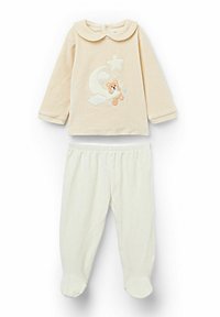 Beżowa bluzka z długim rękawem i okrągłym kołnierzem, z haftowanym misiem, księżycem i gwiazdami; zestawiona z kremowymi spodniami z detalem przy stopach.