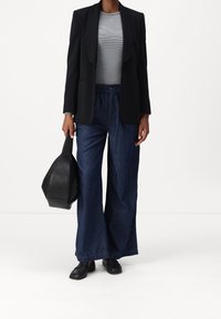 Svart blazer, randig grå topp, vida mörka denimbyxor och svart läderväska. Enkla skor fulländar outfiten, med skräddarsydda linjer och avslappnad passform.