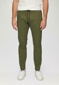 Olijfgroene, taps toelopende joggerbroeken van lichtgewicht stof met een drawstring taille. Gecombineerd met witte sneakers voor een casual look.