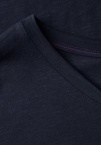Námořnická modrá T-shirt s výstřihem do V, vyrobená z hladké, texturované tkaniny se decentním melírováním a růžovým prošíváním na výstřihu.