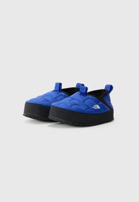 Kék steppelt slip-on cipők fekete gumitalppal, két kék húzófüllel és logóval az oldalán. Könnyű és párnázott kialakítás.