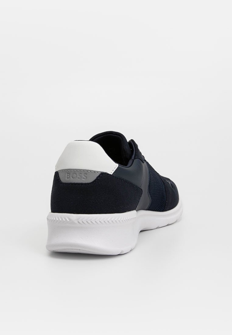 Baskets de sport bleu marine avec un talon blanc et une semelle en caoutchouc. Présente des accents en mesh et en tissu texturé, avec un logo de marque en relief au niveau du talon.