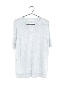 Jasnoszary dzianinowy sweter z krótkimi rękawami raglanowymi, prążkowanym dekoltem oraz teksturowymi akcentami na ramionach i u dołu. Zwisający z czarnego wieszaka.