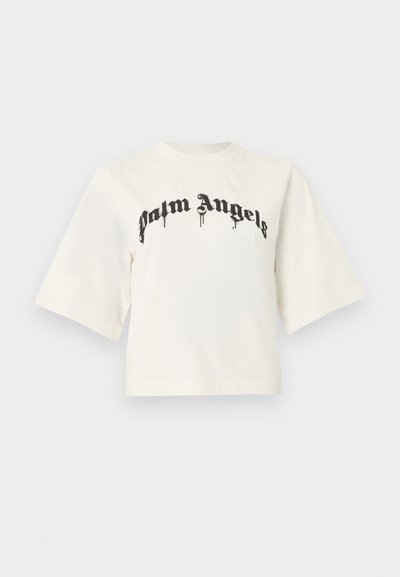 Biely krátky tričko so širokými rukávmi a čiernym gotickým nápisom "Palm Angels" cez hruď.