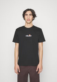 Sort bomulds T-shirt med et cirkulært, farverigt "ellesse" logo på fronten. Klassisk crew neck design med korte ærmer og afslappet pasform.