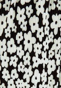 Černobílá plisovaná látka s květinovým vzorem malých bílých květin na tmavém pozadí s viditelnou texturou.