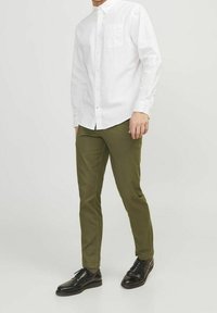 White long-sleeve button-up shirt with a chest pocket, paired with olive green slim-fit pants and black dress shoes. Smooth fabric, tailored fit.