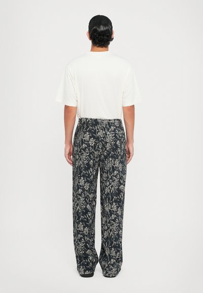 Weißes kurzärmliges T-Shirt kombiniert mit locker sitzenden navyblauen, floral gemusterten Hosen. Der Stoff weist ein strukturiertes Design in hellen Farben auf.