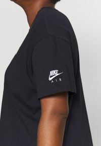 Camiseta de algodón negra con mangas cortas, que presenta un logotipo de Nike Air bordado en la manga izquierda. Diseño de cuello redondo simple.