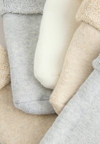 Stablede bløde strikkede og frotté sokker i beige, creme og lys grå nuancer med synlige teksturer.