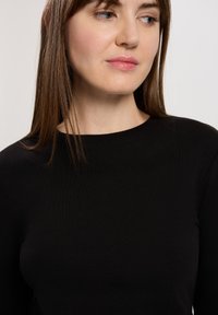 Czarna, prążkowana bluzka z długim rękawem i okrągłym dekoltem. Gładka tekstura i dopasowany krój podkreślają smukłą sylwetkę odzieży.