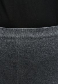 Κοντινό πλάνο σκούρου γκρι πλεκτού υφάσματος με ριμπ τελείωμα και ορατή κάθετη ραφή.