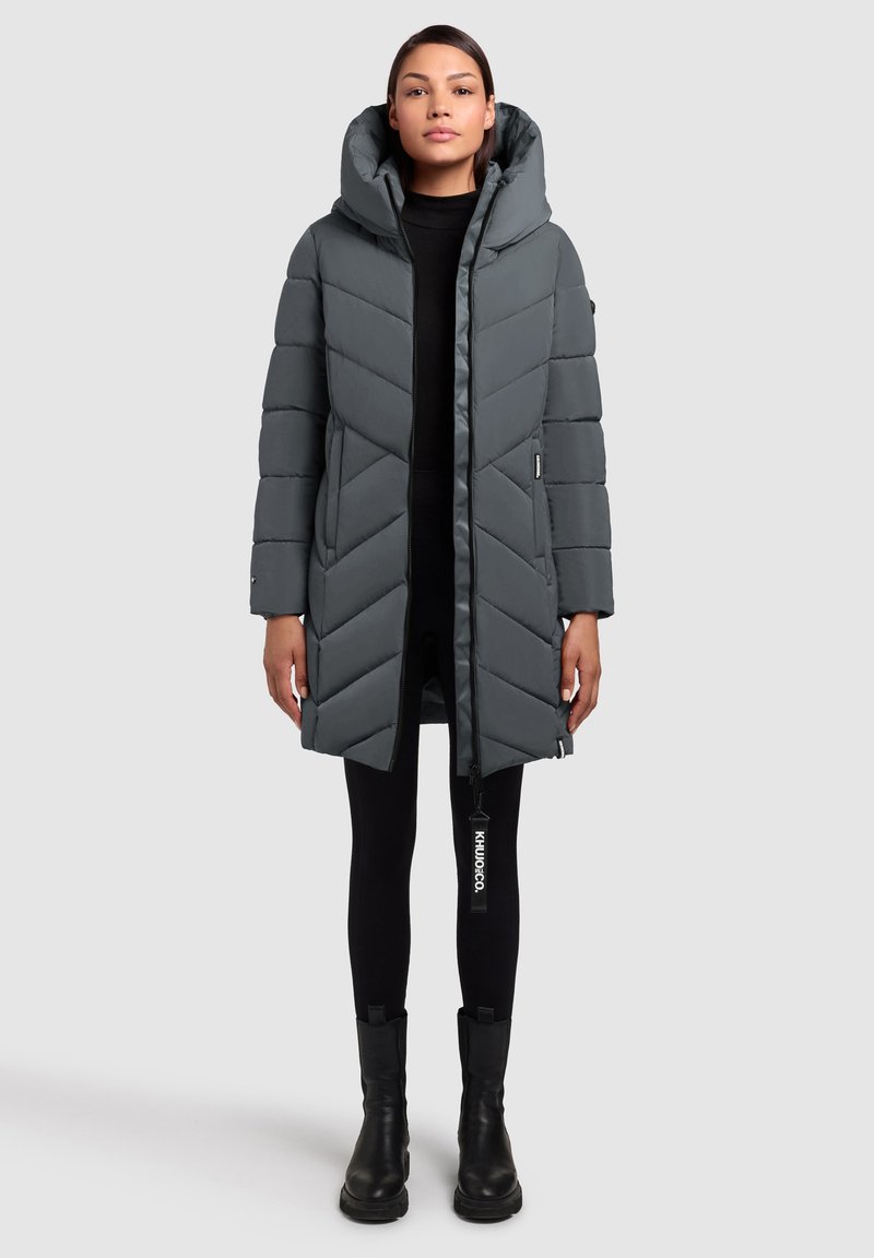 Grå dunjakke med et chevronmønster, lynlåslukning og en stor hætte. Har sidelommer og et mærketag på lynlåsen.