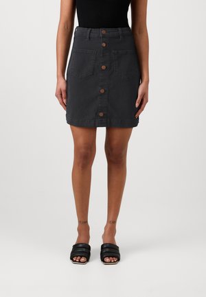 Gray denim mini skirt with front button closure, two front pockets, and raw hem. Paired with black slide sandals.