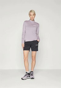 Hele lilla pika varrukatega topp, millel on seisma collar, koos mustade lühikeste pükstega. Kandmisel hallid ja mustad spordijalatsid. Lihtne disain, funktsionaalne sobivus.