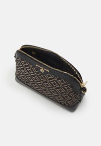 Sorte og brune mønstrede Michael Kors taske lavet af stof og læder med guldfarvet hardware og lynlåslukning. Har et prægede logo.