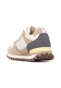 Zapatillas beige y gris que combinan materiales de malla y ante, cuentan con una suela texturizada, acentos blancos y un talón acolchado con un borde amarillo.