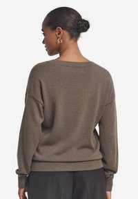 Brauner Pullover mit weicher Textur, lockerer Passform, weiter Halsöffnung, überschnittenen Schultern, geripptem Saum und Bündchen.