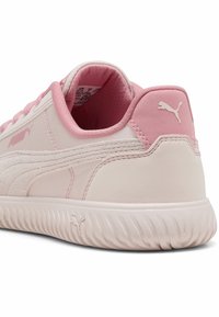 Scarpa sportiva rosa chiaro con una finitura morbida e strutturata, caratterizzata da un logo Puma bianco e un interno ammortizzato, angolata per mostrare il dettaglio del tallone.