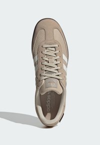 Brown suede and mesh sneaker with white stripes, thick laces, padded collar, and contrasting dark sole. Features branded tongue and insole.