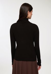 Czarny sweter z golfem, wykonany z prążkowanej tkaniny, z długimi rękawami i dopasowanym krojem, w połączeniu z brązową spódnicą o rozkloszowanym fasonie.