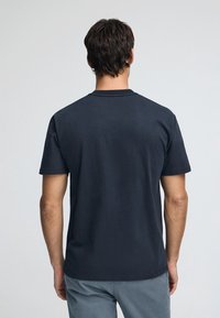 Dunkelblaue Baumwoll-T-Shirts mit Rundhalsausschnitt und kurzen Ärmeln, ausgestattet mit einem schlichten Rückendesign. Schlichte, figurbetonte Form, weicher Stoff.