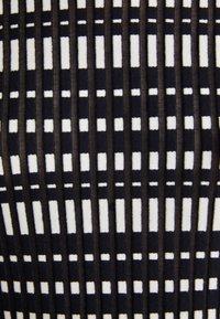 Stoff in Schwarz-Weiß mit abwechselnden vertikalen und horizontalen Streifen, der eine strukturierte, weiche Oberfläche aufweist.