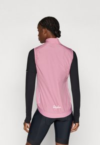 Chaleco de ciclismo ligero en color rosa con cuello alto, dobladillo elástico y bolsillos laterales. Presenta acentos reflectantes y un logo en la parte posterior.
