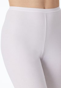 Leggings blancs en tissu doux et extensible. Présentent un ajustement lisse et serré avec une large ceinture. Pas de motifs ou d'accents visibles.