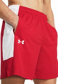 Pantalones cortos deportivos rojos hechos de un tejido ligero, con un panel lateral blanco, cintura elástica y bolsillos a ambos lados.