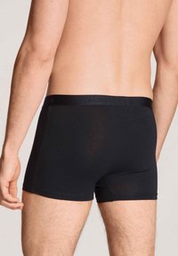 Zwarte boxershorts met een gladde textuur en een elastische tailleband, met een aansluitend ontwerp en een korte beenlengte.