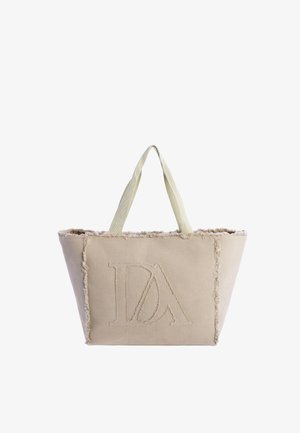 Bolso tote beige con bordes deshilachados y asas anchas, con un gran logo "DA" cosido en el centro delantero.