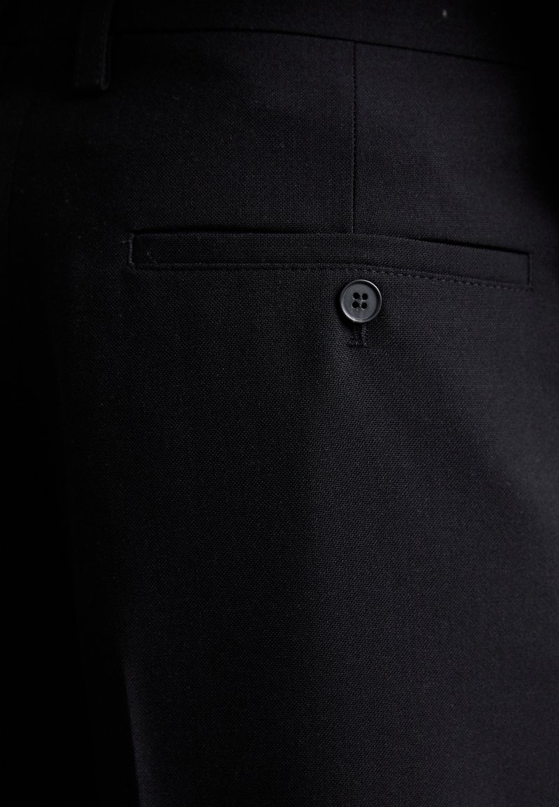 Black tailored trousers featuring a smooth fabric texture, a discreet back pocket, and a black button closure for secure fastening.