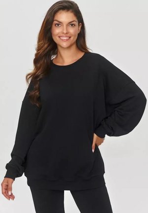 Czarny, oversize sweter z długimi, luźnymi rękawami i okrągłym dekoltem. Miękki materiał o gładkiej fakturze; dopasowany w mankietach i u dołu.