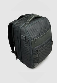 Mochila gris con un patrón texturizado de rombos. Cuenta con varios compartimentos con cremallera, correas ajustables y un asa resistente.