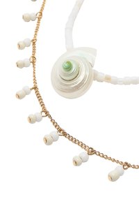 Dwa naszyjniki z zawieszką w kształcie spiralnej muszli, białymi koralikami oraz złotym łańcuszkiem z wiszącymi akcentami w postaci koralików. Teksturalne materiały i mieszane kolory.
