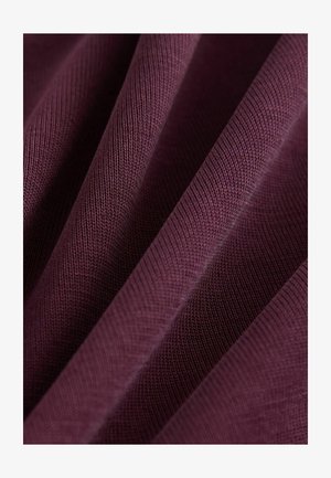 Material texturat de culoare burgundă cu un model nervurat, prezentând pliuri și detalii de drapaj care evidențiază structura materialului și a țesăturii.