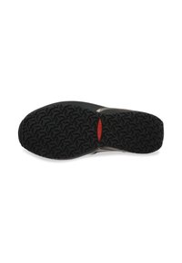 Crna gumena površina cipele s teksturiranim uzorkom za prianjanje i crvenim ovalnim logotipom u središtu, izolirano na bijeloj pozadini.